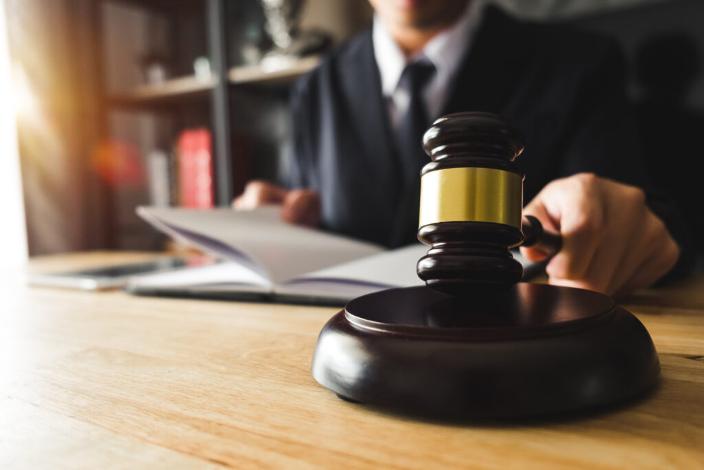 justice and law concept.Male judge in a courtroom the gavel, working with digital tablet computer on wood table in morning light